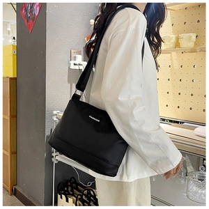 Détail du sac bandoulière en nylon noir imperméable avec texte blanc et sangle large