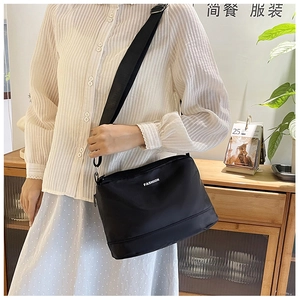 Détail du sac bandoulière en nylon noir imperméable avec lettrage fashion et bandoulière large