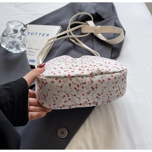 Detail view of floral print canvas bucket bag on grey suit and white bedding background