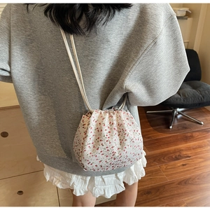Floral drawstring crossbody bag with pink pattern shown being worn for a casual lifestyle look