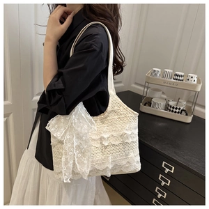 Detail of multi-layered white lace tote bag with a large bow in a warm indoor setting