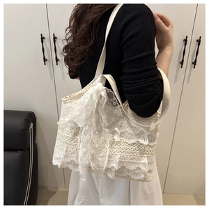 Detail of white lace tote bag with layered floral embroidery and decorative bow design