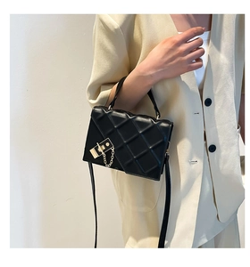 Close-up of black leather bag with geometric texture and gold chain in casual style