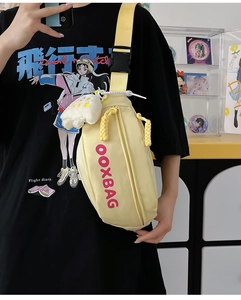 Détail du sac bandoulière jaune avec logo OOXBAG, tissu en nylon et pendentif en peluche