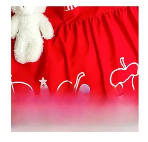 Detail of red tote bag with white apple prints, star patterns and a plush charm