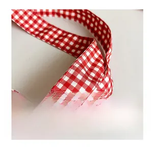 Detail of red and white gingham pattern travel bag handle with reinforced stitching