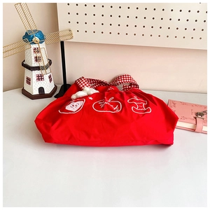 Detail of red canvas tote bag with apple illustration and cute white plush charm pendant
