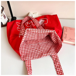 Detail of red canvas tote with white heart print and red checkered inner lining