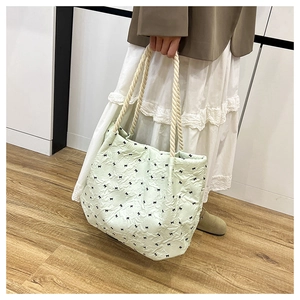 Detail of light green pleated tote bag with black bow prints and beige woven rope handles