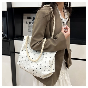 Close-up of a white tote bag with bubble fabric texture and black bow patterns