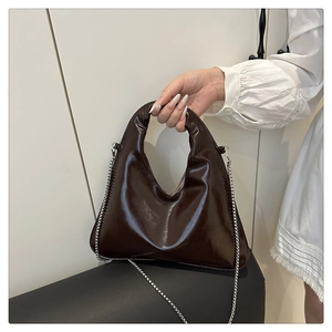 Dettaglio ravvicinato della borsa in pelle verniciata marrone con catena in argento