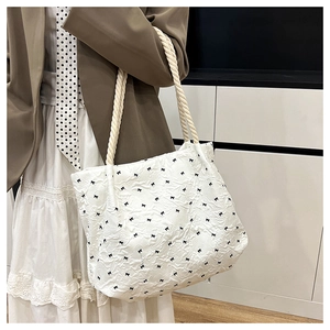 Detail of white tote bag with black bow embroidery and thick woven rope handles