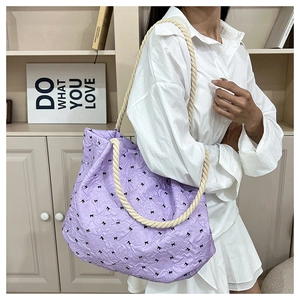 Detail of light purple pleated tote bag with black bows and beige braided rope handle