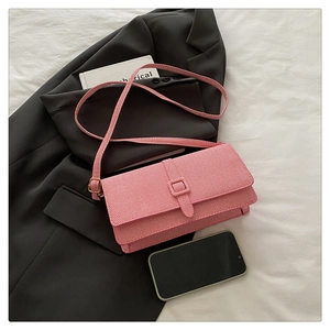 Close-up of pink crossbody bag with diagonal weave texture on grey blazer