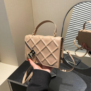 Elegant quilted handbag in beige with a gold chain buckle shown in a hand-held studio shot