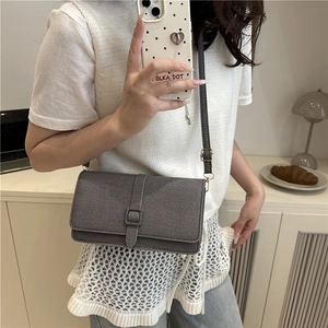 Chic gray crossbody bag with denim texture and metallic buckle shown in lifestyle setting