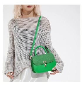 Détail du sac bandoulière vert citron avec rabat pailleté et fermoir doré sur modèle