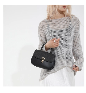 Détail du rabat à paillettes noires et de la boucle dorée sur un sac bandoulière chic