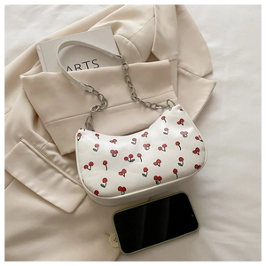 Détail du sac hobo blanc à motif cerise avec chaîne argentée sur un fond esthétique doux