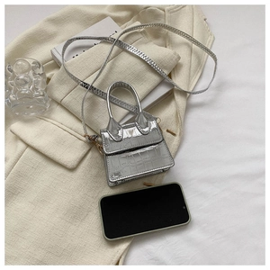 Silver crocodile texture micro bag compared to smartphone showing miniature size
