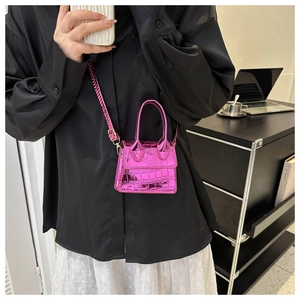 Mini-Handtasche in Pink mit Krokodilprägung, Griff und Metallkette am Modell
