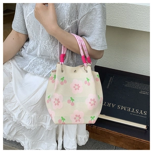 Detail der gestrickten Beuteltasche mit rosa Blumenmuster und geflochtenen Seilgriffen