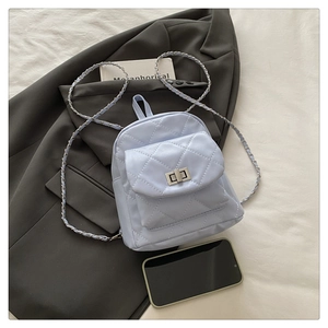 Detailed view of light blue quilted mini backpack with silver twist lock on a grey blazer