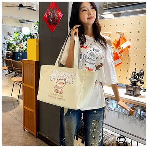 Asian model wearing an off-white corduroy tote bag with panda print in a cozy store