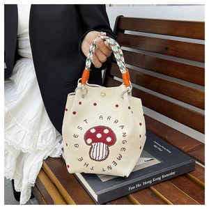 Detail der gestrickten Beuteltasche mit Pilzmuster und gewebtem grünem Griff