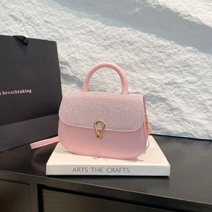 Sac à bandoulière rose pailleté avec poignée et fermoir doré sur boîte décorative