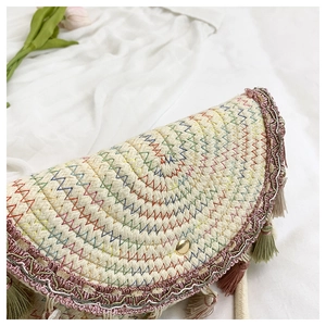 Détail du sac bohème en paille avec broderie arc-en-ciel, pompons et fermoir doré