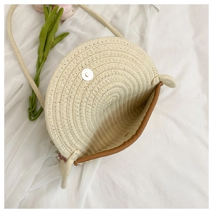 Detail of handwoven straw crossbody bag with brown trim and magnetic snap closure