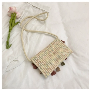 Detail of hand-woven straw crossbody bag with colorful wavy stitching and tassels