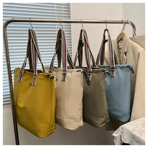 Hanging canvas bucket bags with striped webbing handles in yellow, white, green and blue