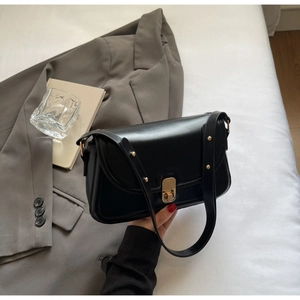 Vue détaillée du sac à bandoulière en cuir noir mat avec fermoir métallique doré vertical