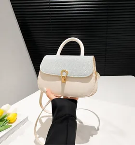 Close-up of cream shoulder bag with silver sequin flap and golden horseshoe clasp