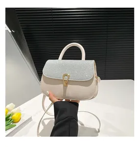 Gros plan du sac crème avec rabat à paillettes argentées et fermoir doré en fer à cheval