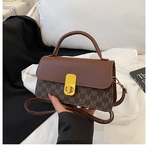 Detail of the vintage brown monogram flap bag featuring a gold clasp and a top handle