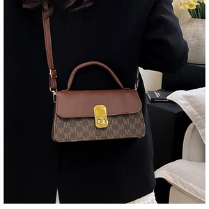 Detail of crossbody bag with brown color-blocking, M-pattern, and golden rotary lock