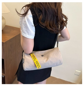 Détail du sac seau en nylon beige avec ruban tissé jaune et étiquette de marque