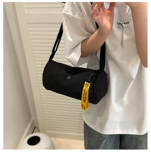 Détail du sac bandoulière cylindrique noir en nylon avec pendentif en sangle jaune