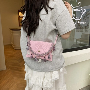 Pink hand-woven saddle bag with fringe trim, crossbody style for summer fashion