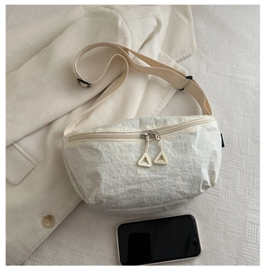 Détail du sac bandoulière en toile blanc cassé avec zips argentés et sangle réglable