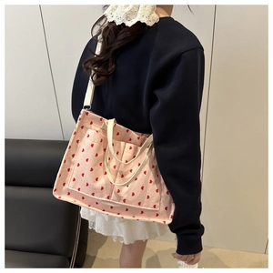 Detailed view of pink corduroy tote bag with red heart print and two front pockets
