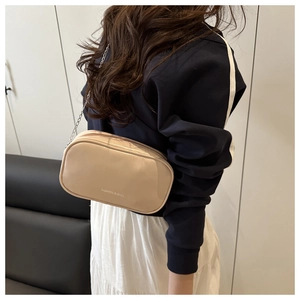 Détail de sac bandoulière beige avec bandoulière chaîne et lettrage pour femmes