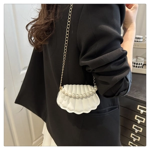 Detail of shell-shaped crossbody bag with pearl embellishments and gold chain strap