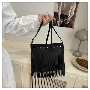 Dettaglio borsa in pelle martellata nera con borchie argentate e lunghe frange decorative