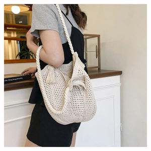 Detail of crochet tote bag with thick rope shoulder strap and bohemian tassels