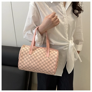 Detailed view of pink and beige Boston bag with monogram pattern held by a model
