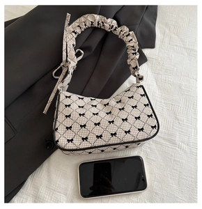 Close-up of beige plaid shoulder bag with black bows and pleated ruffles strap detail